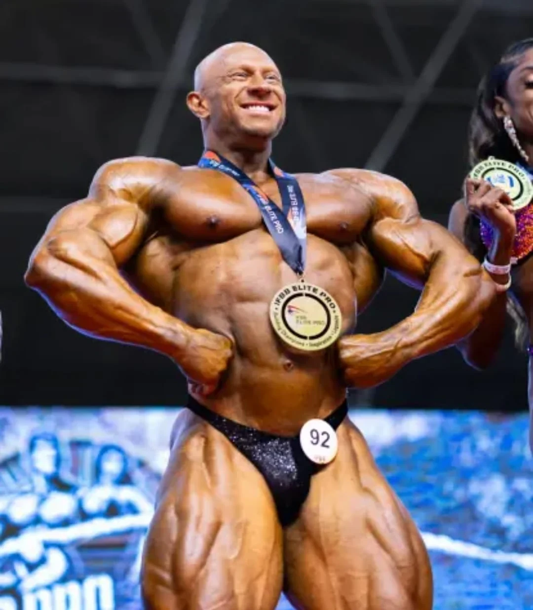 Athlete with an IFBB Elite Pro medal on stage