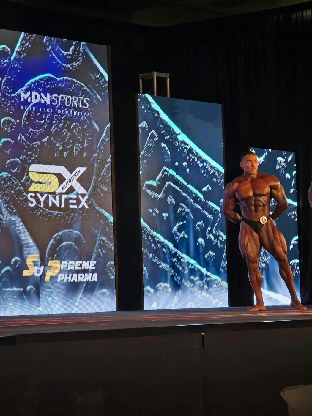 Athlete on stage in front of the screen with the Syntex logo